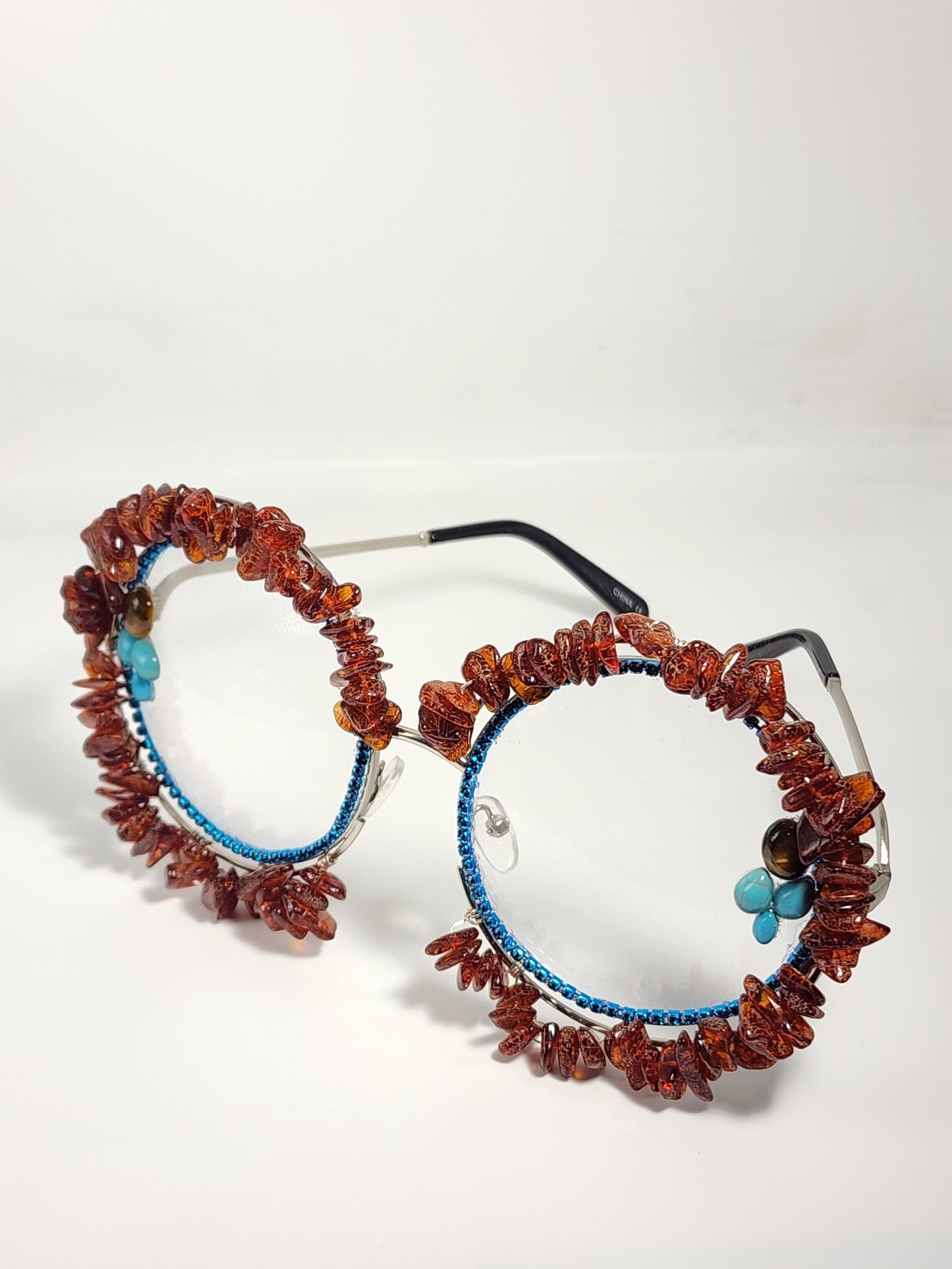 Round eyeglass with blue frame embellished with brown stones