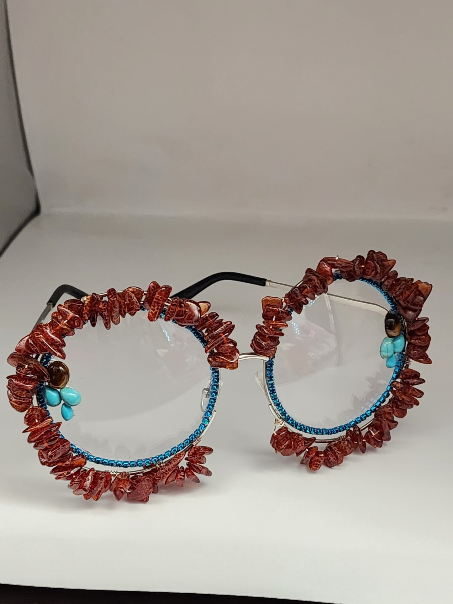 Round eyeglass with blue frame embellished with brown stones