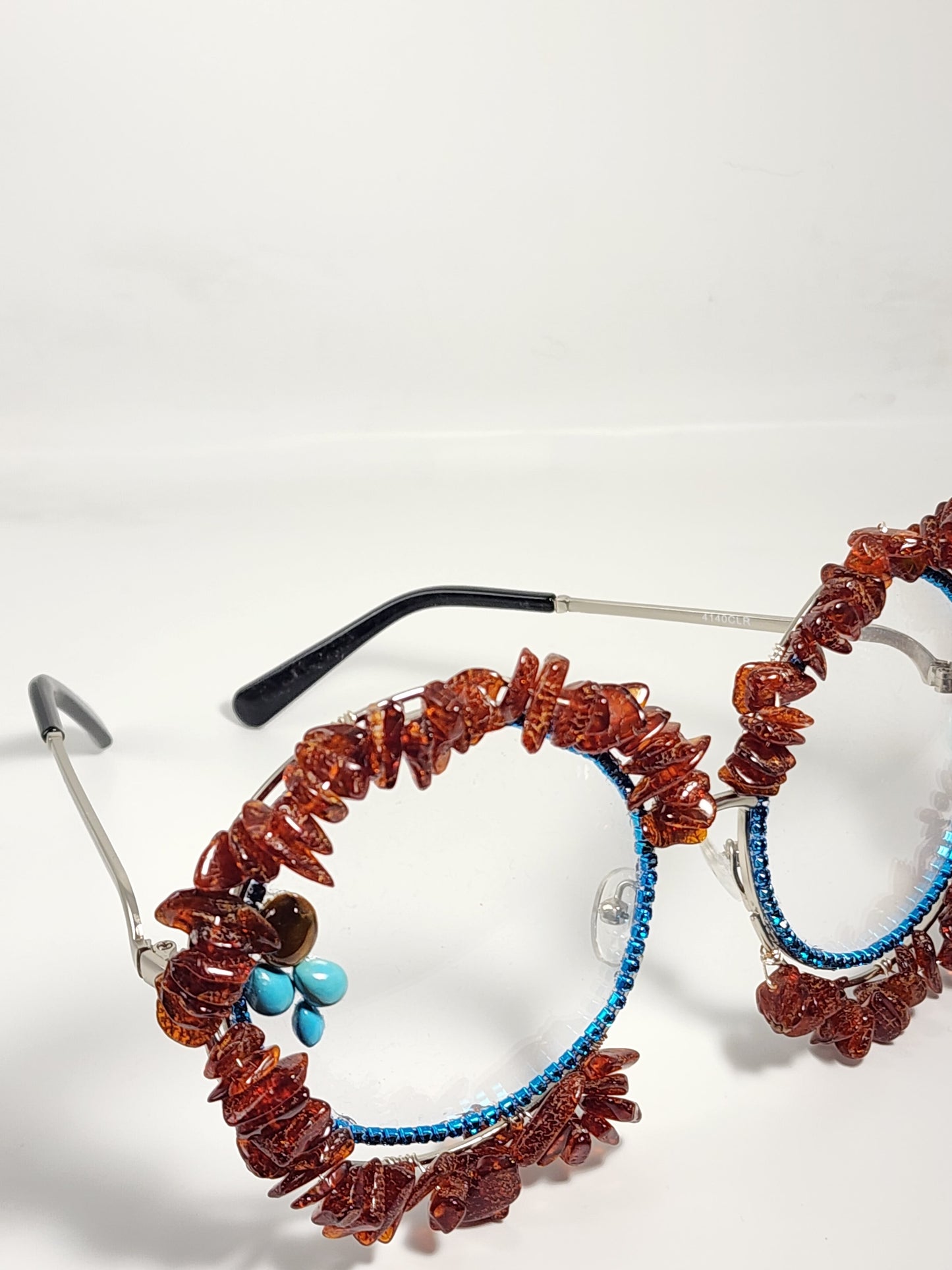 Round eyeglass with blue frame embellished with brown stones
