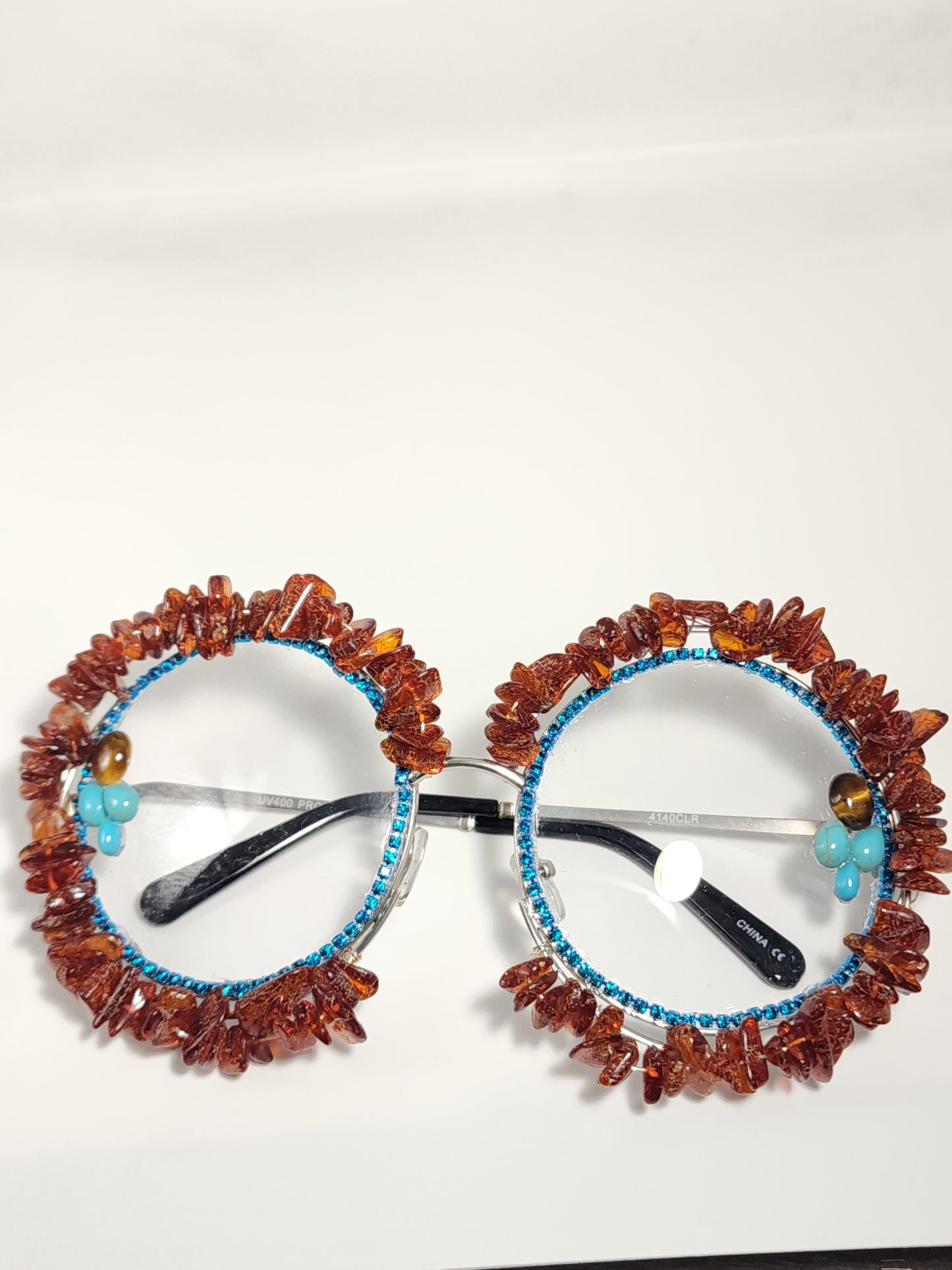 Round eyeglass with blue frame embellished with brown stones