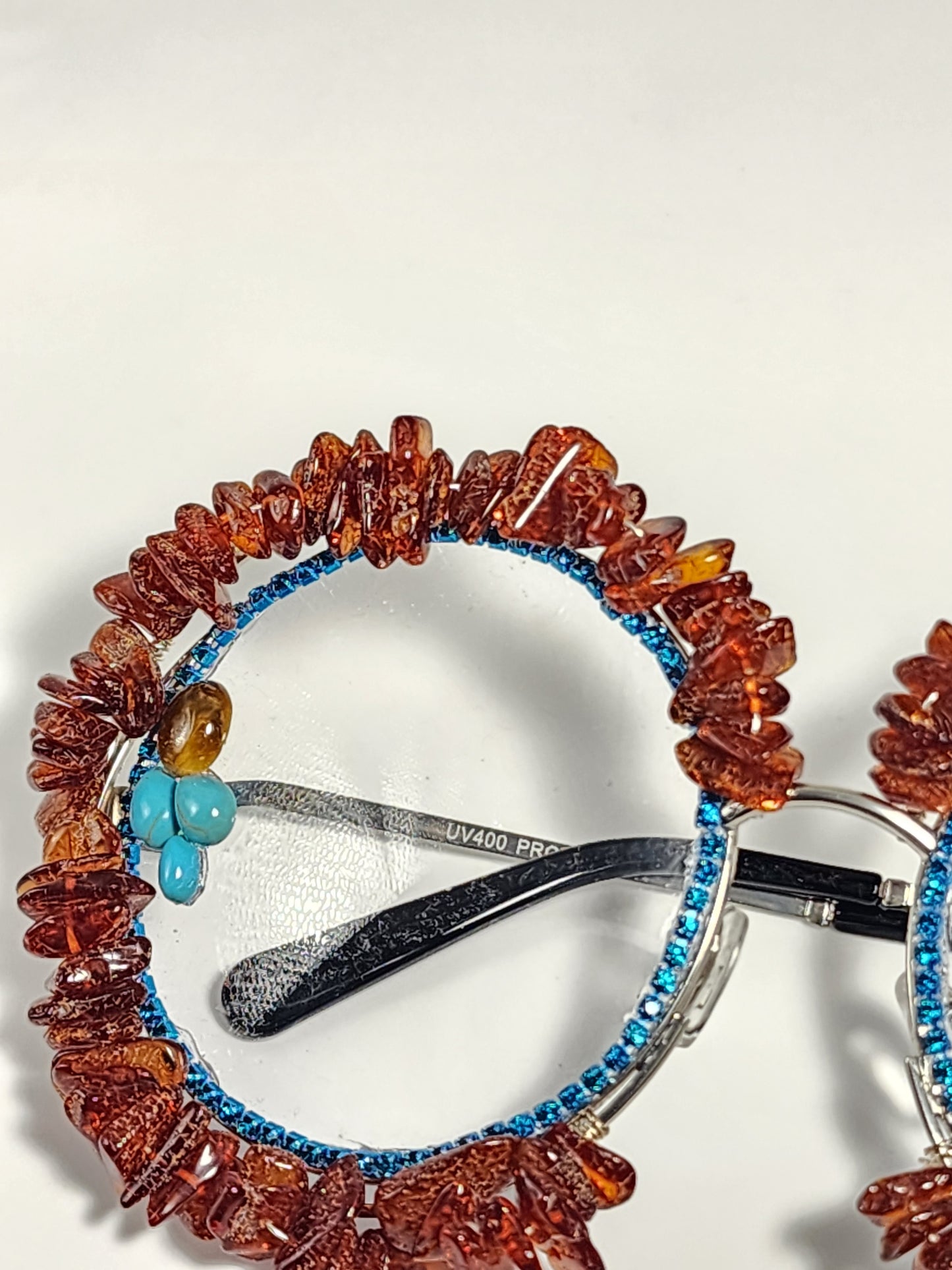 Round eyeglass with blue frame embellished with brown stones